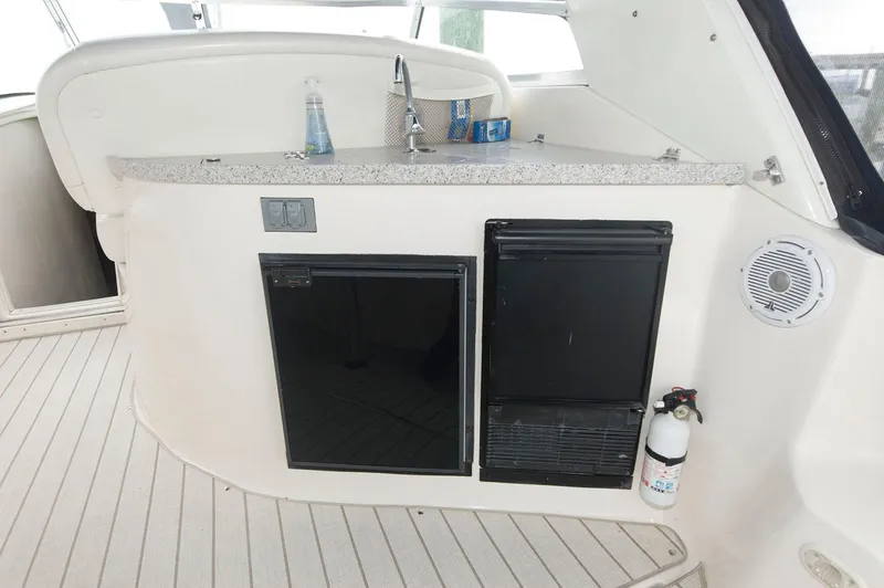 Slide: The Image of 2002 Rinker 342 Fiesta Vee boat kitchenette with sink, mini fridge, and fire extinguisher. - 7