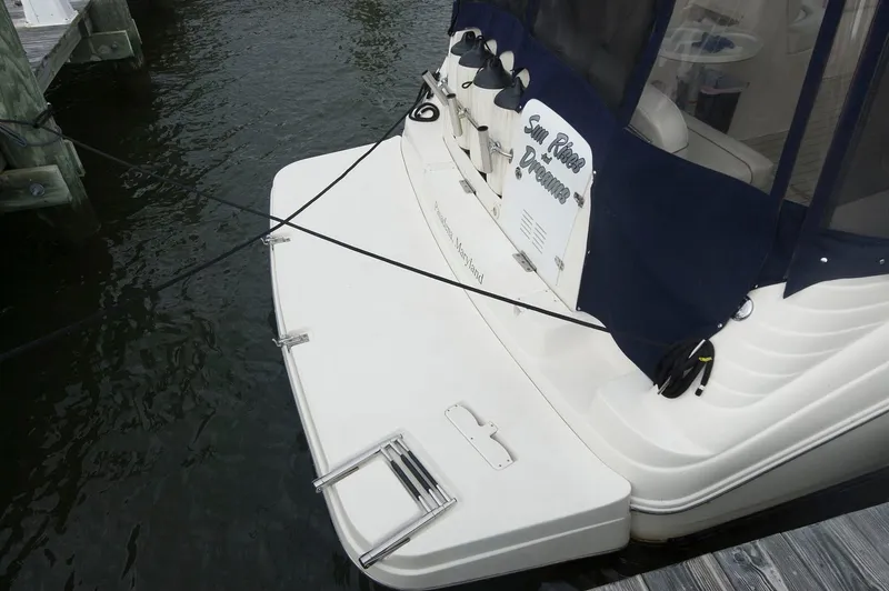 Slide: The Image of 2002 Rinker 342 Fiesta Vee boat docked, featuring a swim platform and navy blue canopy. - 8
