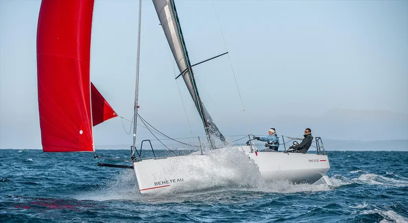 Slide: The Image of 2024 Beneteau First 27 sailboat with red spinnaker navigating ocean waves. - 2