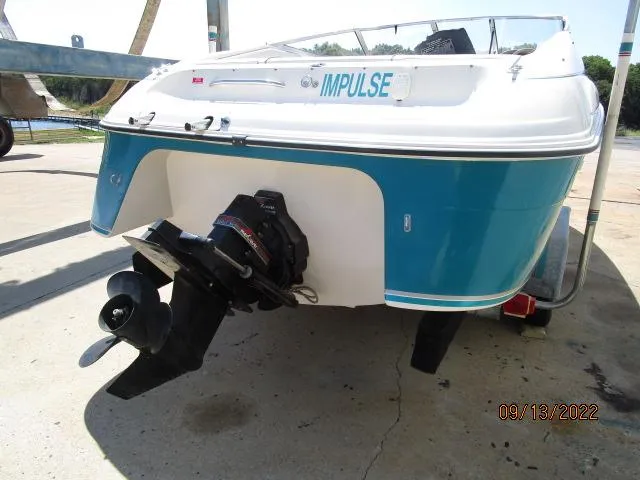 Slide: The Image of 1995 Regal VALANTI 222 SE boat, rear view, blue and white, docked, with visible propeller. - 2