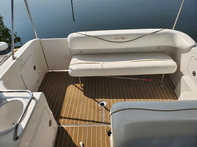 Slide: The Image of 2003 Sea Ray 260 Sundancer boat interior with white seating and wood-patterned flooring. - 13