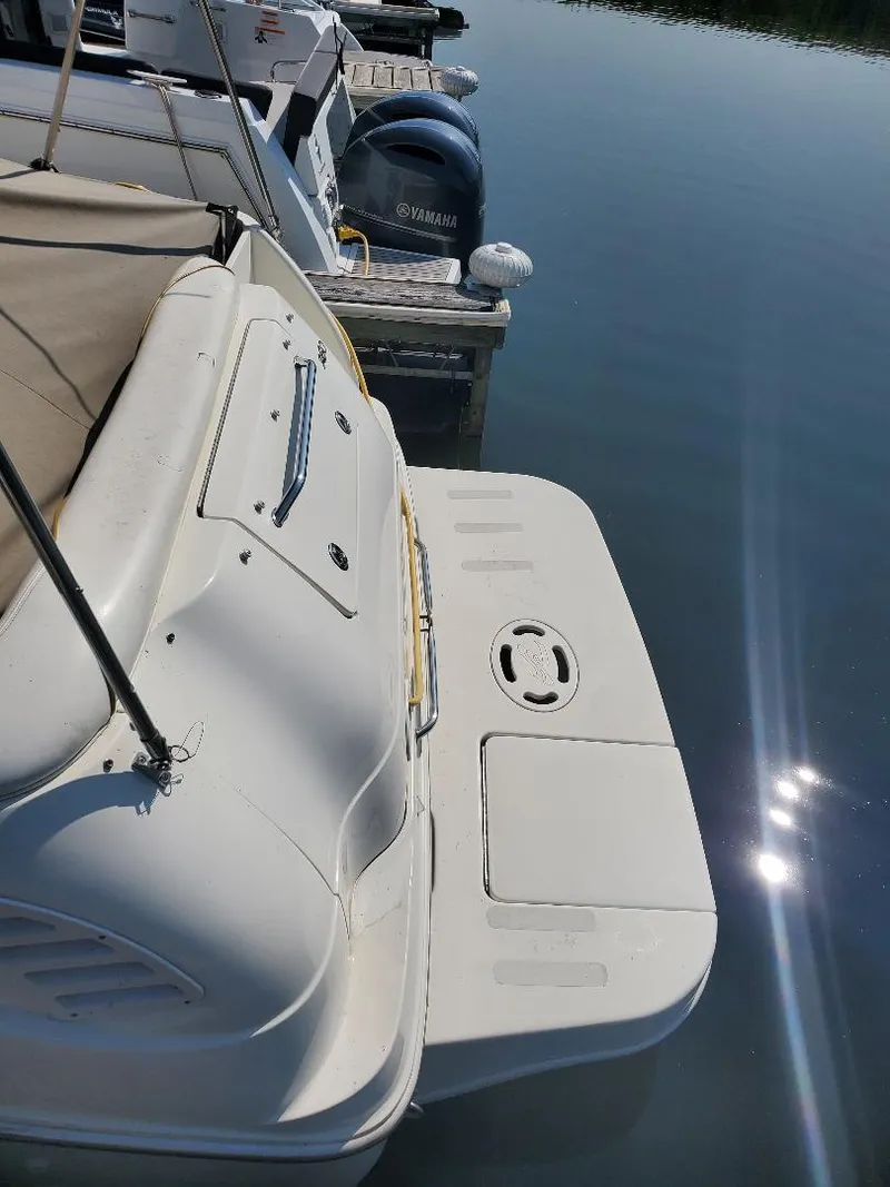 Slide: The Image of 2003 Sea Ray 260 Sundancer docked, showing rear deck and calm water reflection. - 14