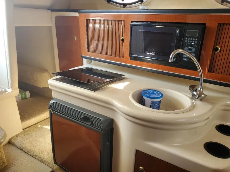 Slide: The Image of 2003 Sea Ray 260 Sundancer cabin with kitchenette, featuring microwave, sink, and compact fridge. - 15