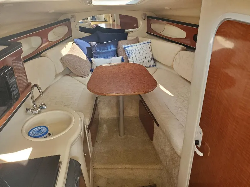 Slide: The Image of Interior of 2003 Sea Ray 260 Sundancer boat with cozy seating and wooden table. - 5