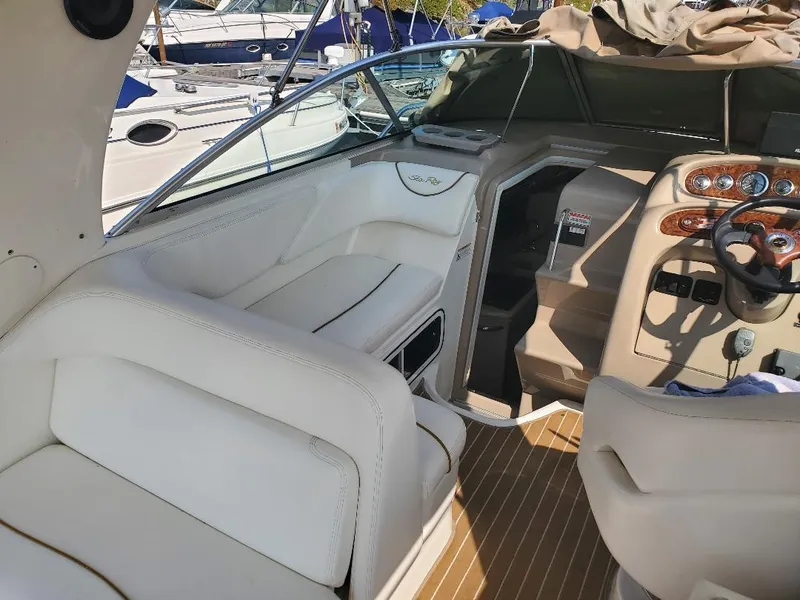 Slide: The Image of 2003 Sea Ray 260 Sundancer interior with white seating and wooden dashboard. - 6