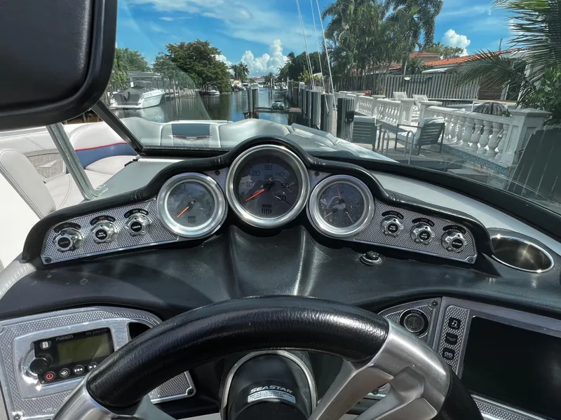 Slide: The Image of 2014 MasterCraft X-55 boat dashboard with gauges and controls, docked in a canal. - 24