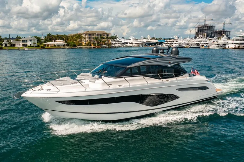 The Image of A sleek white yacht cruises through a harbor with other boats in the background. - 0