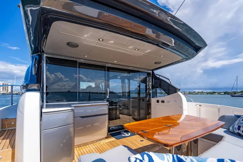 Slide: The Image of The 2020 Princess V60 features a sleek aft deck with a wooden table and cushioned seating. - 11