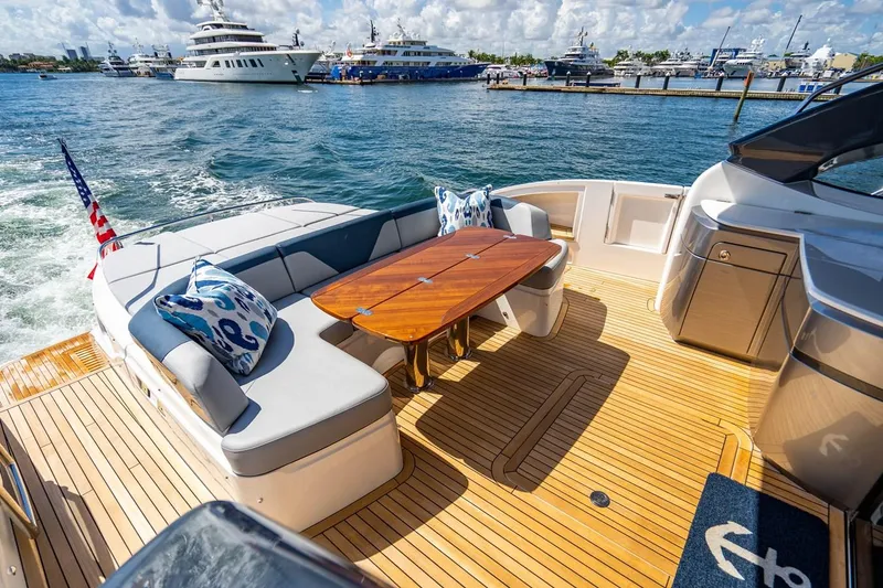 Slide: The Image of The image shows the aft deck of a 2020 Princess V60 yacht with a wooden table and seating. - 13