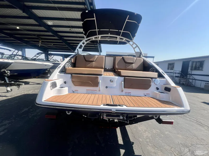 Slide: The Image of 2025 Yamaha Boats 252SE with spacious deck and seating, under a covered marina. - 4
