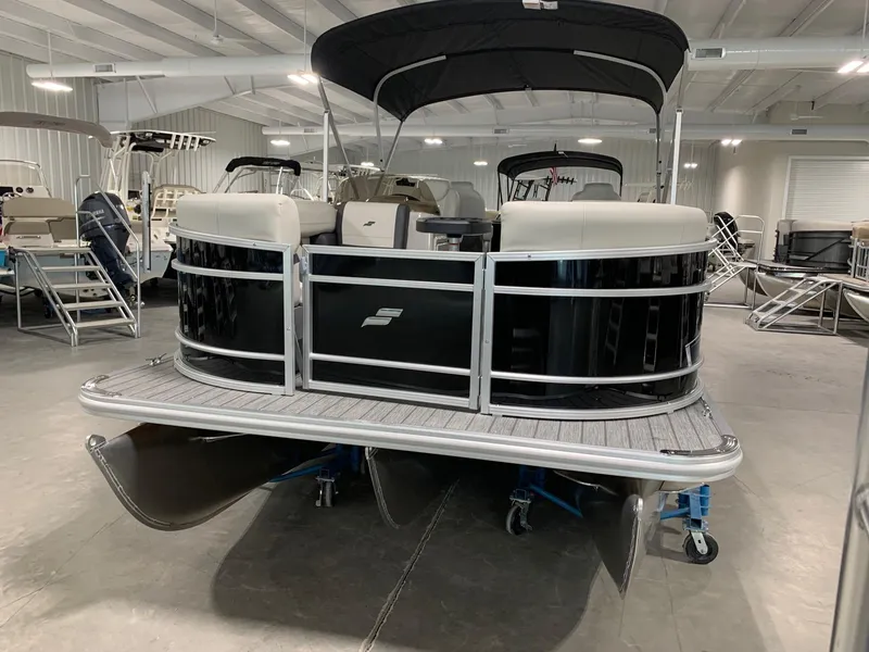 Slide: The Image of 2024 Starcraft EX22 FD pontoon boat in showroom, black exterior, under canopy. - 2