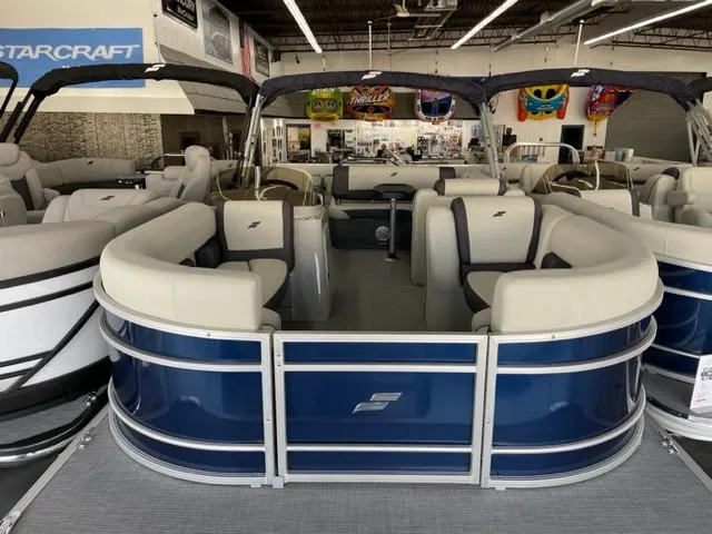 Slide: The Image of 2023 Starcraft EX 22 Q pontoon boat with blue and white seating in showroom. - 3