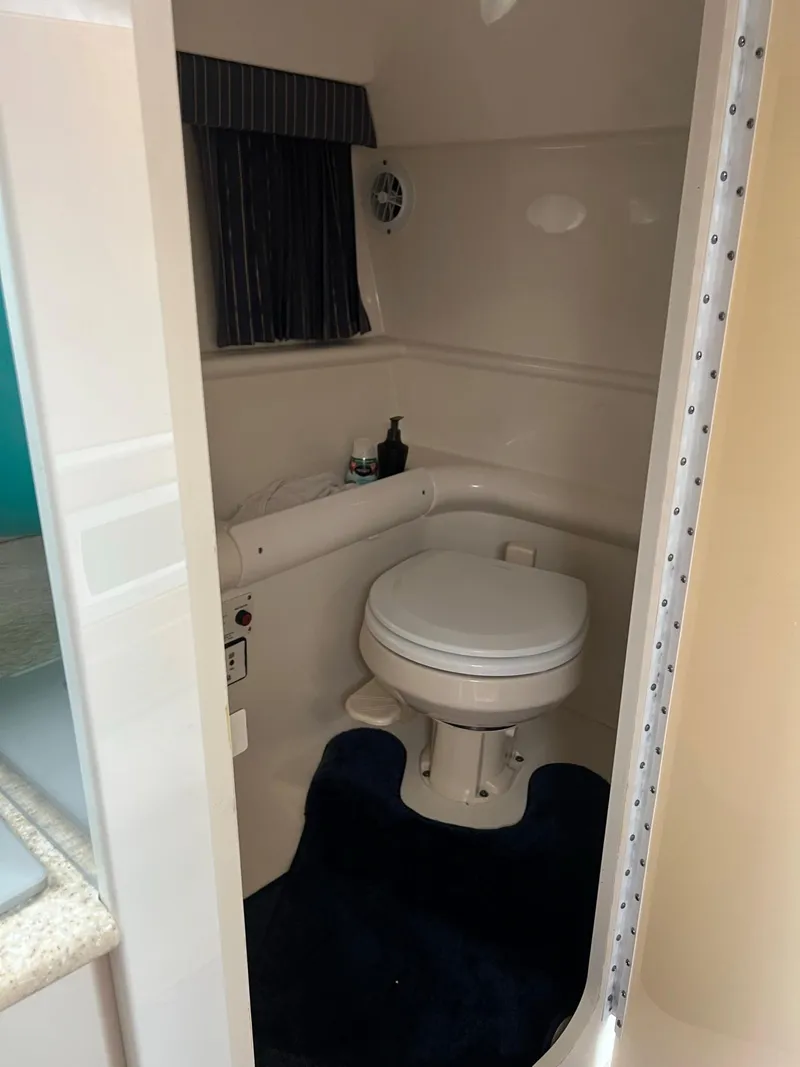 Slide: The Image of 2003 Formula 330 Sun Sport boat bathroom with toilet, blue rug, and compact design. - 14