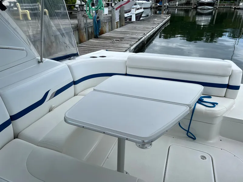 Slide: The Image of 2003 Formula 330 Sun Sport boat interior with white seating and table by a dock. - 6