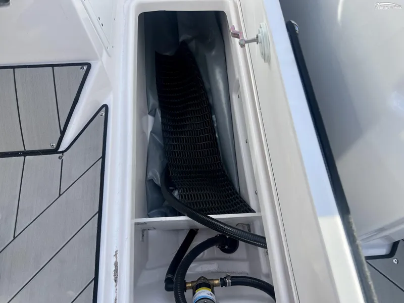 Slide: The Image of 2025 Yamaha Boats 252XE storage compartment with black mat and hoses. - 7