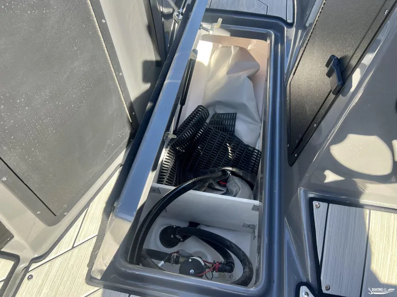 Slide: The Image of Open storage compartment in 2025 Yamaha Boats 222XE, showing hoses and equipment. - 3