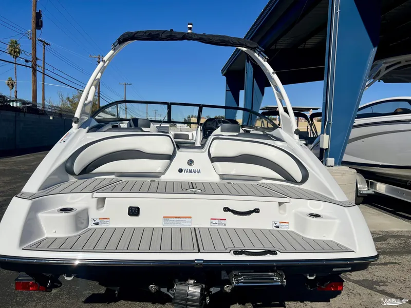 Slide: The Image of 2025 Yamaha Boats 195S, rear view, sleek design, docked under blue canopy. - 2