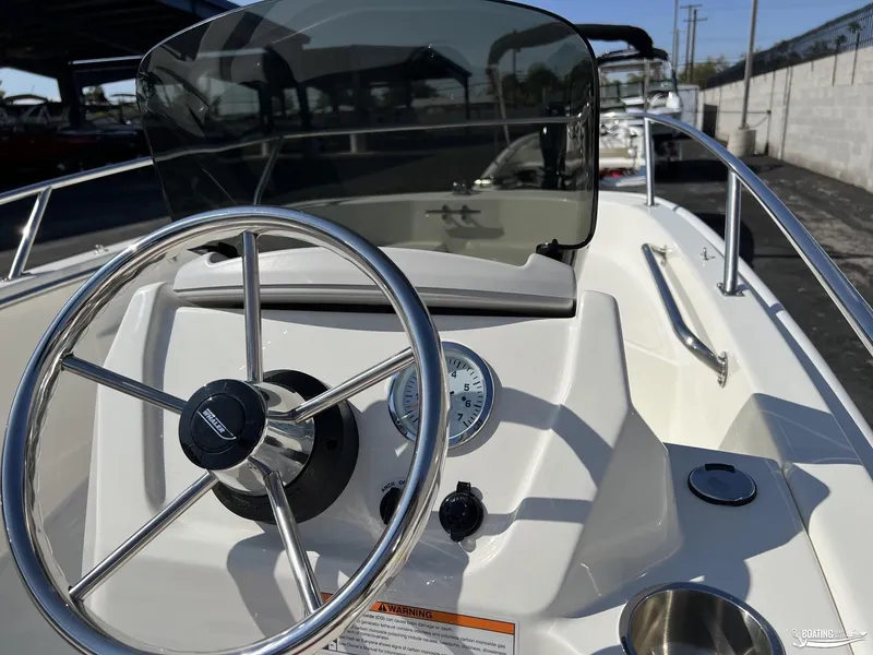 Slide: The Image of 2024 Boston Whaler 130 Super Sport boat steering console with stainless steel wheel. - 3