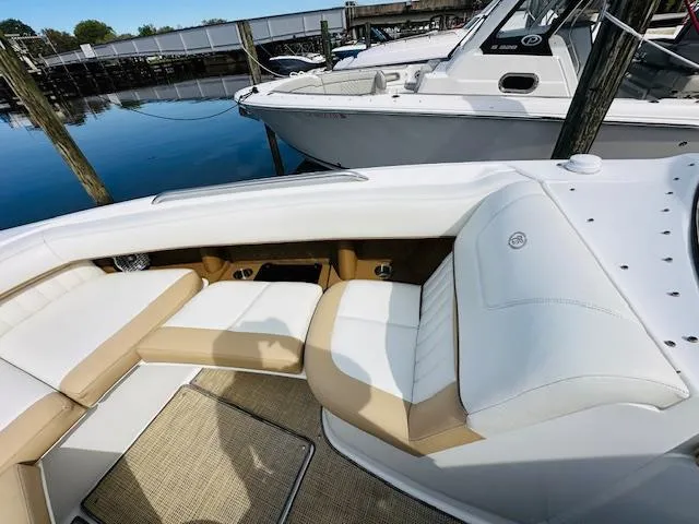 Slide: The Image of 2015 Cobalt 302 boat interior with white and beige seating at a marina. - 23