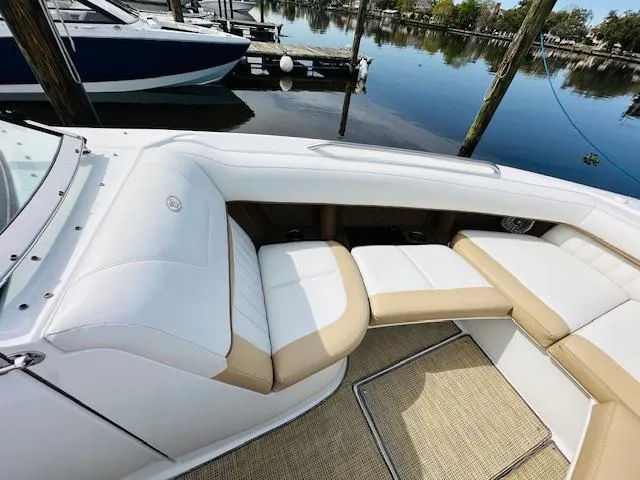 Slide: The Image of 2015 Cobalt 302 boat interior with white and beige seating at a marina. - 24