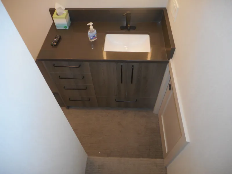 Slide: The Image of Compact bathroom vanity with dark countertop, sink, and storage drawers in Adonia Obsession Trip #12, 2021. - 32