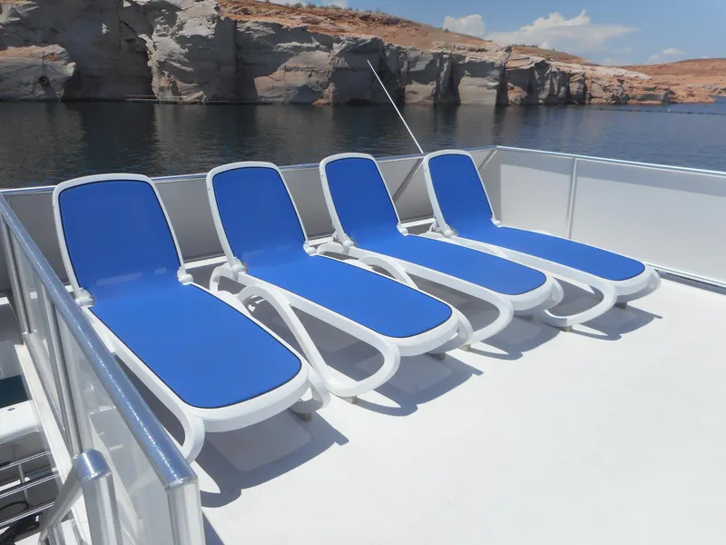Slide: The Image of Four blue lounge chairs on Adonia Obsession Trip #12 boat deck, 2021, near rocky shoreline. - 5
