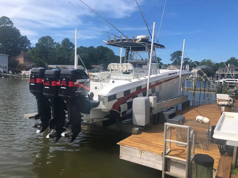 The Image of 2003 Fountain 38TE boat with triple Mercury outboard engines docked at a marina. - 0