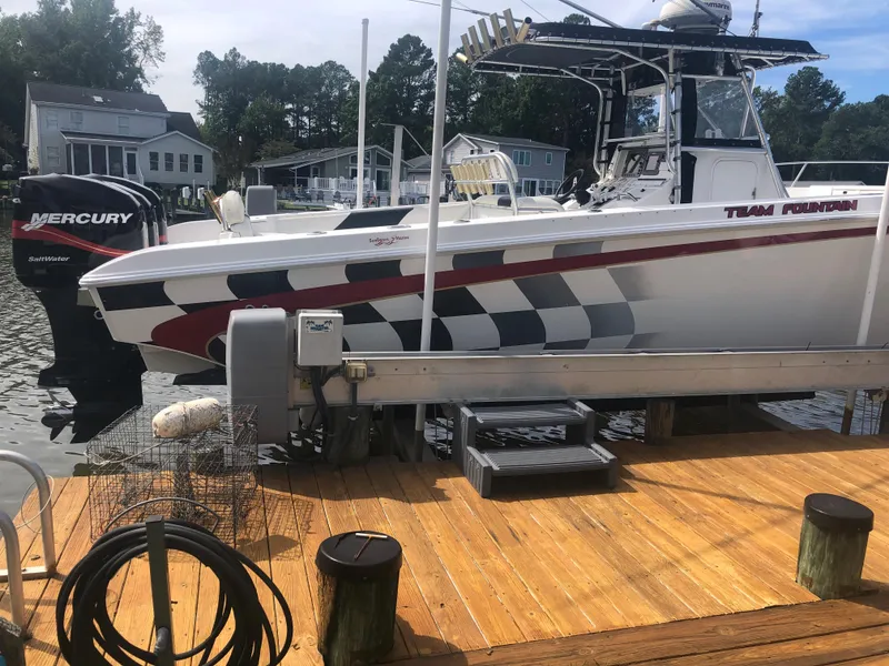 Slide: The Image of 2003 Fountain 38TE boat docked, featuring Mercury outboard engines and checkered flag graphics. - 4