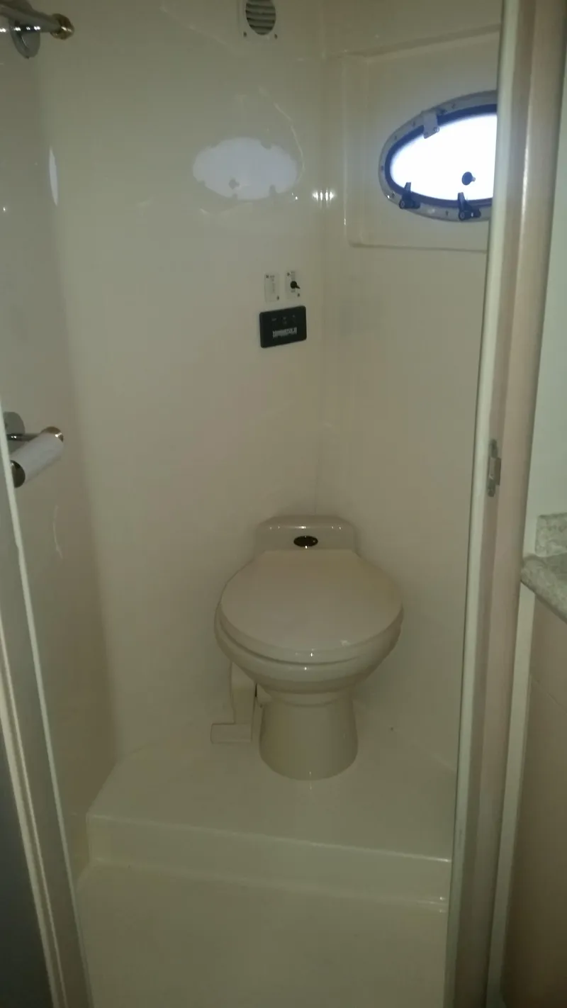 Slide: The Image of 1999 Carver 530 Voyager Pilothouse bathroom with toilet and porthole window. - 32