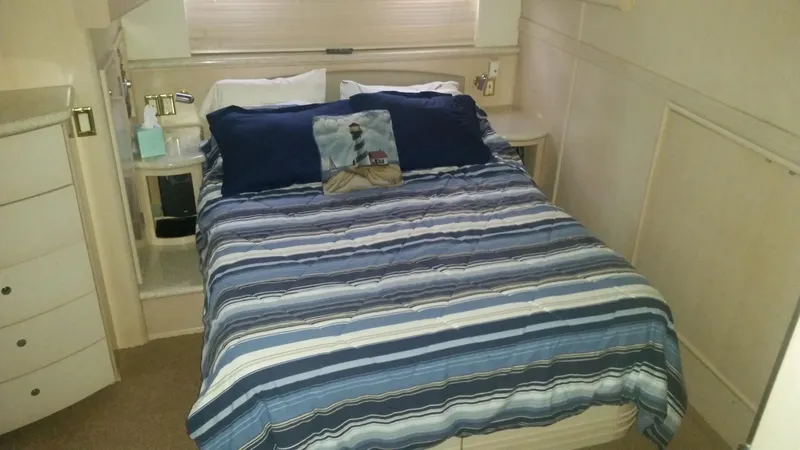 Slide: The Image of 1999 Carver 530 Voyager Pilothouse bedroom with striped bedding and nautical-themed pillow. - 30