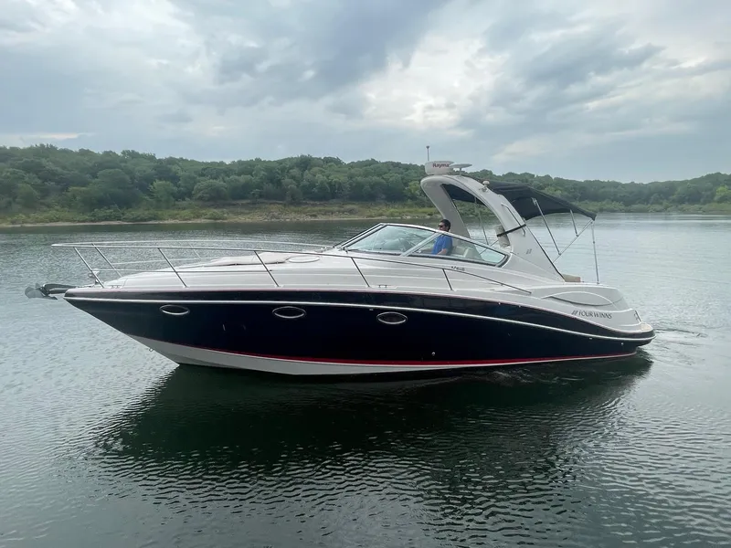 The Image of 2009 Four Winns V318 boat cruising on a calm lake under a cloudy sky. - 0