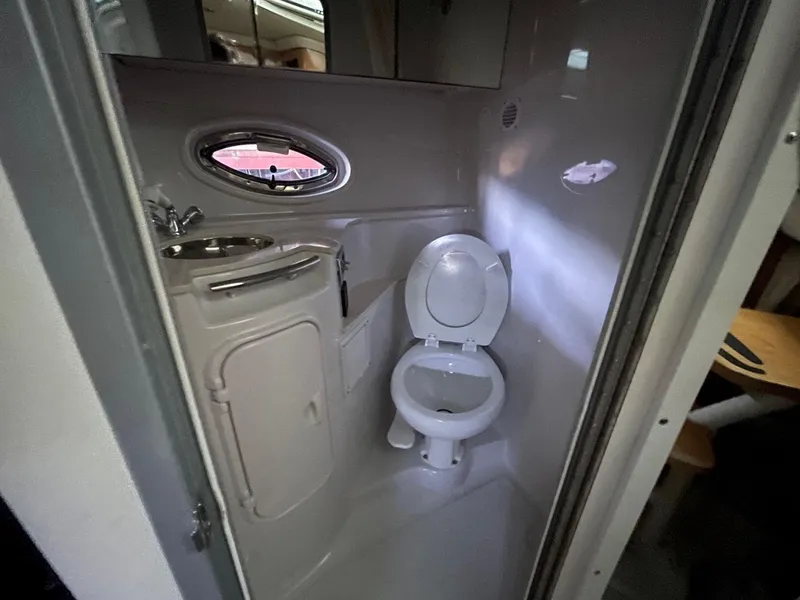 Slide: The Image of 2009 Four Winns V318 boat bathroom with toilet, sink, and porthole window. - 14