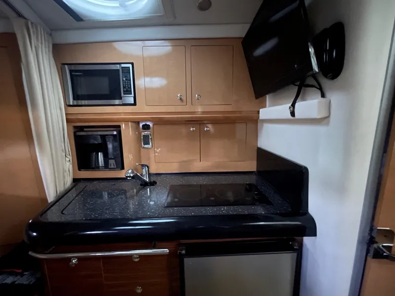 Slide: The Image of 2009 Four Winns V318 yacht kitchen with microwave, coffee maker, sink, stove, and TV. - 20
