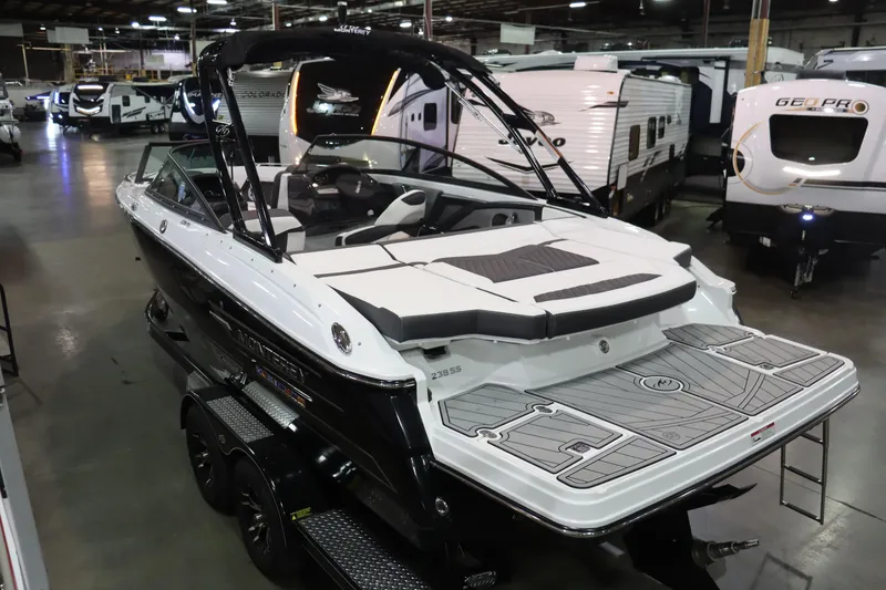 Slide: The Image of 2023 Monterey 238 Super Sport boat displayed indoors with other recreational vehicles. - 4