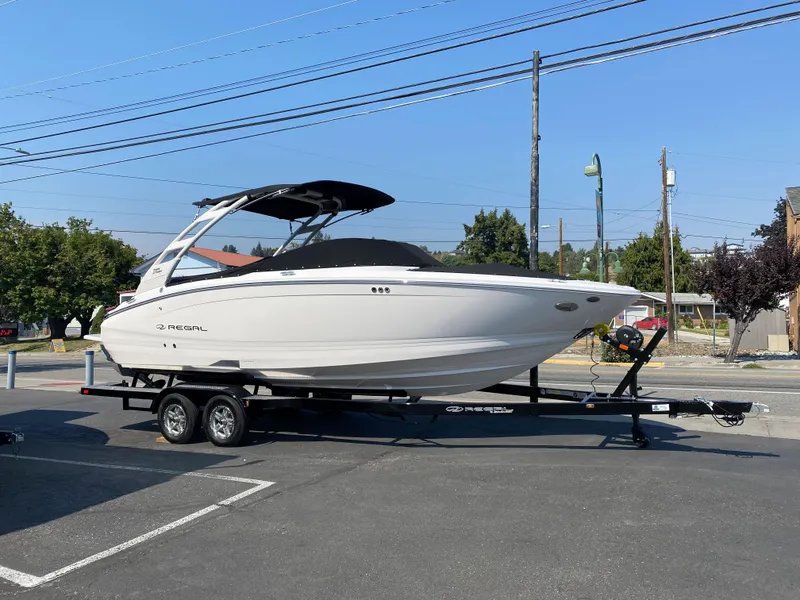Slide: The Image of 2023 Regal LS6 Surf boat on a trailer in a parking lot. - 2