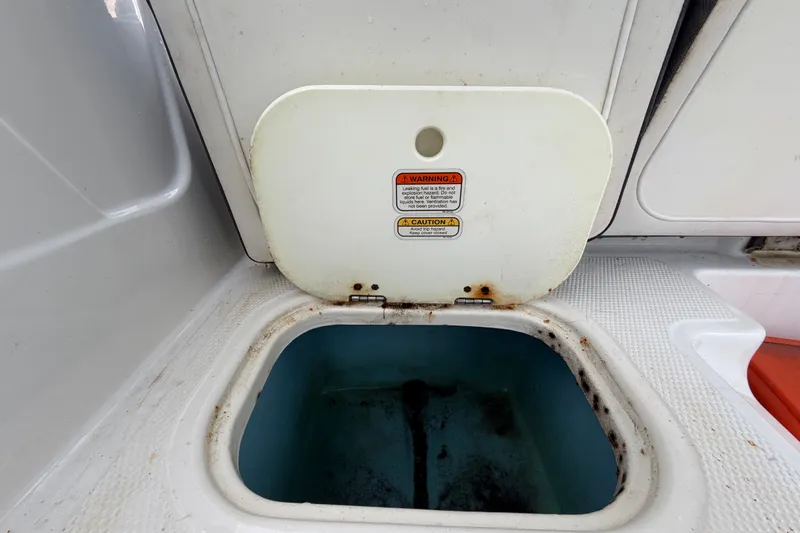 Slide: The Image of Open storage compartment on 2019 Tahoe 550 TS boat, showing interior and warning labels. - 54