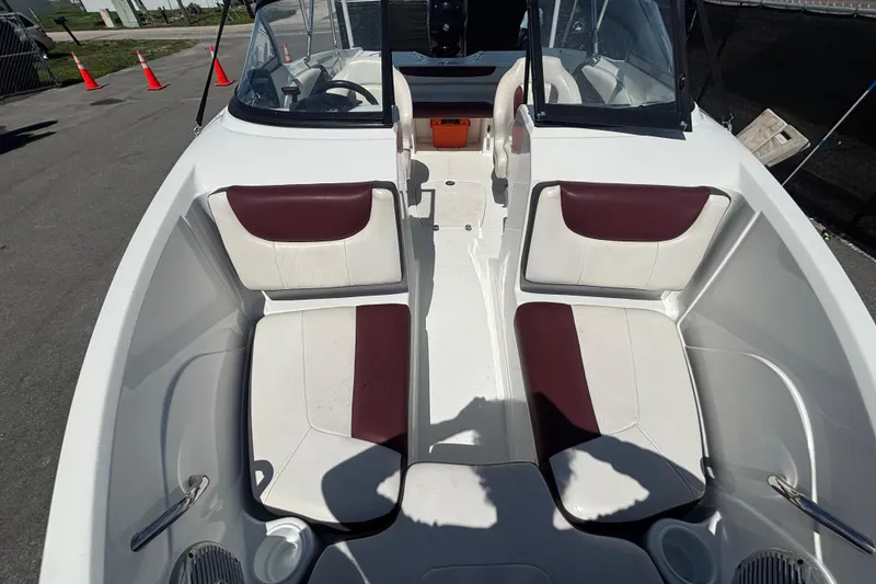 Slide: The Image of 2019 Tahoe 550 TF boat interior with white and maroon seating, docked outdoors. - 36