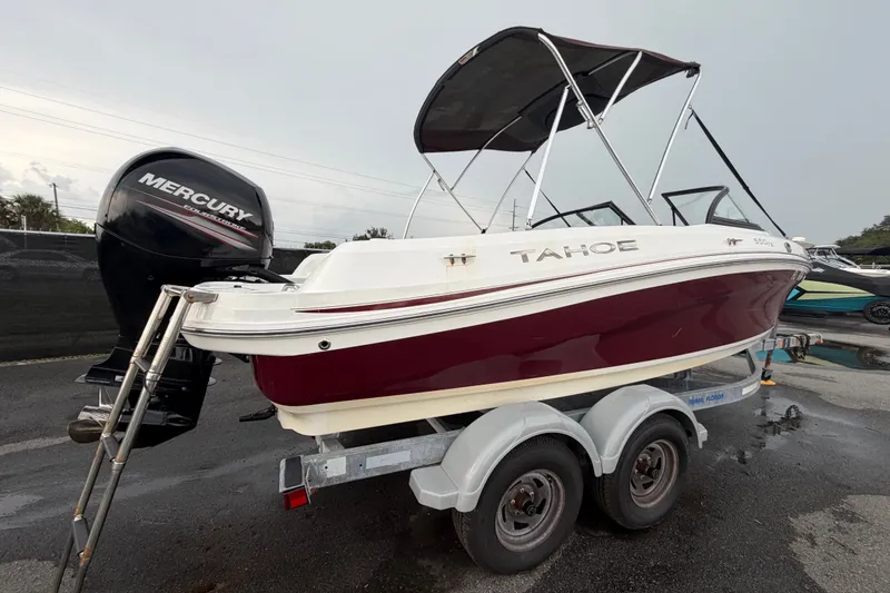 Slide: The Image of 2019 Tahoe 550 TS boat on trailer with Mercury outboard engine, parked outdoors. - 2