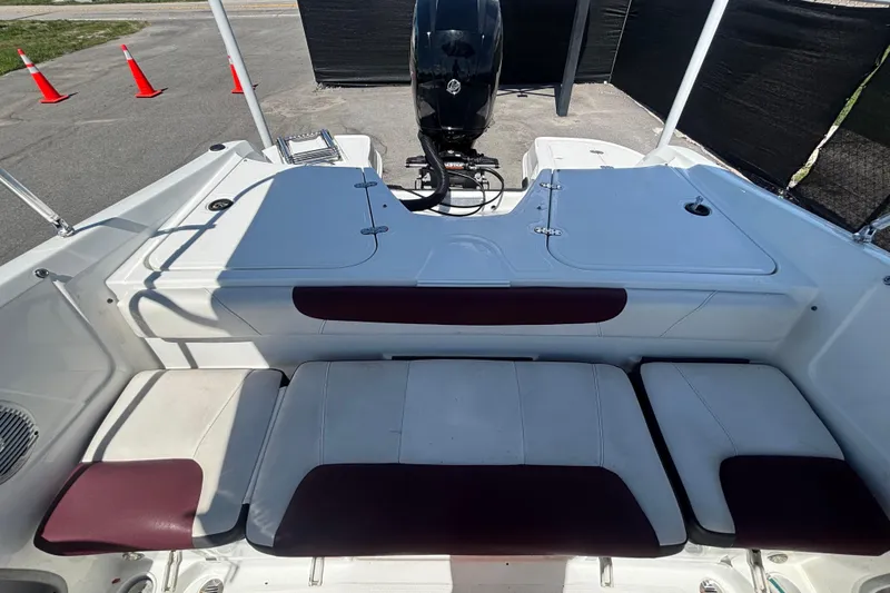 Slide: The Image of 2019 Tahoe 550 TF boat interior with cushioned seating and motor, parked outdoors. - 50