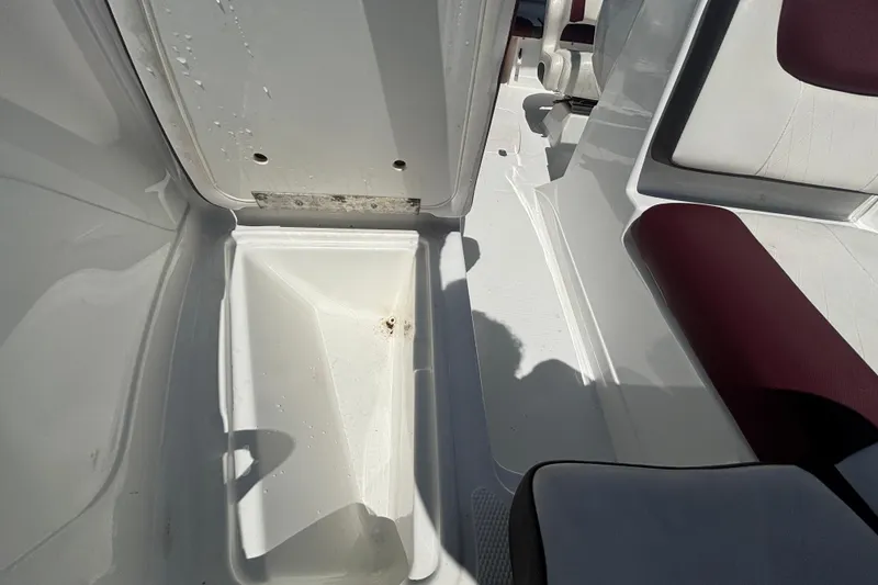 Slide: The Image of Open storage compartment in 2019 Tahoe 550 TF boat, featuring white interior and maroon seating. - 40