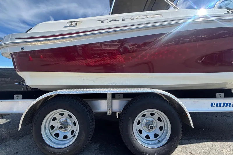 Slide: The Image of 2019 Tahoe 550 TF boat on trailer, featuring red and white design under a clear sky. - 64