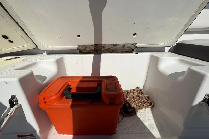 Slide: The Image of Open storage compartment in 2019 Tahoe 550 TS boat with orange toolbox and coiled rope. - 55