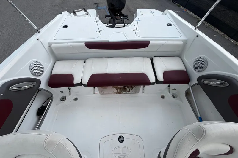 Slide: The Image of 2019 Tahoe 550 TS boat interior with white and maroon seating, speakers, and storage compartments. - 49