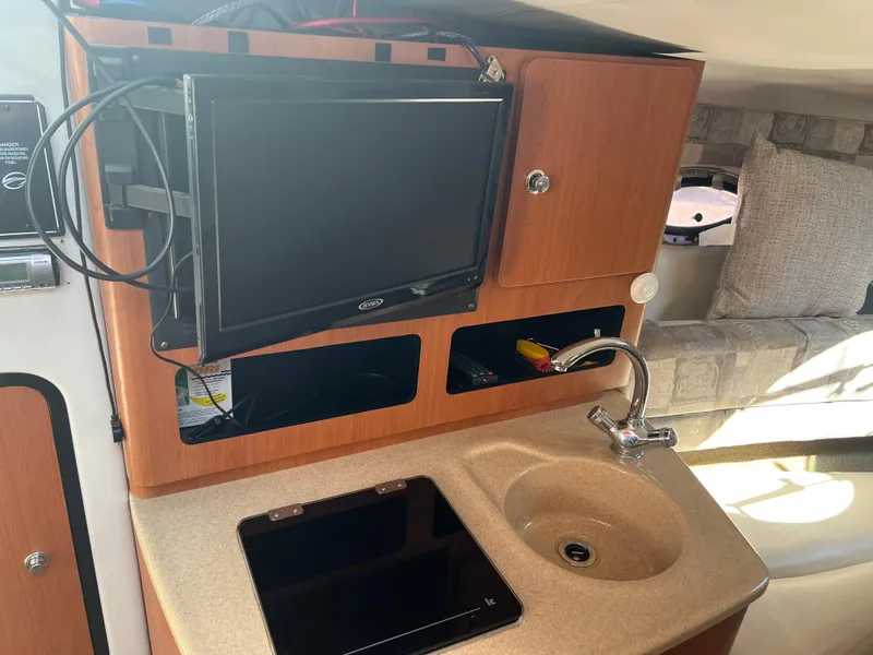 Slide: The Image of 2007 Crownline 250 CR boat interior with sink, TV, and storage cabinets. - 16