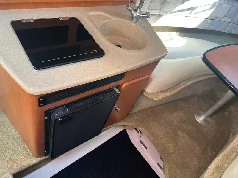 Slide: The Image of 2007 Crownline 250 CR cabin kitchenette with sink, stove, and mini-fridge. - 17