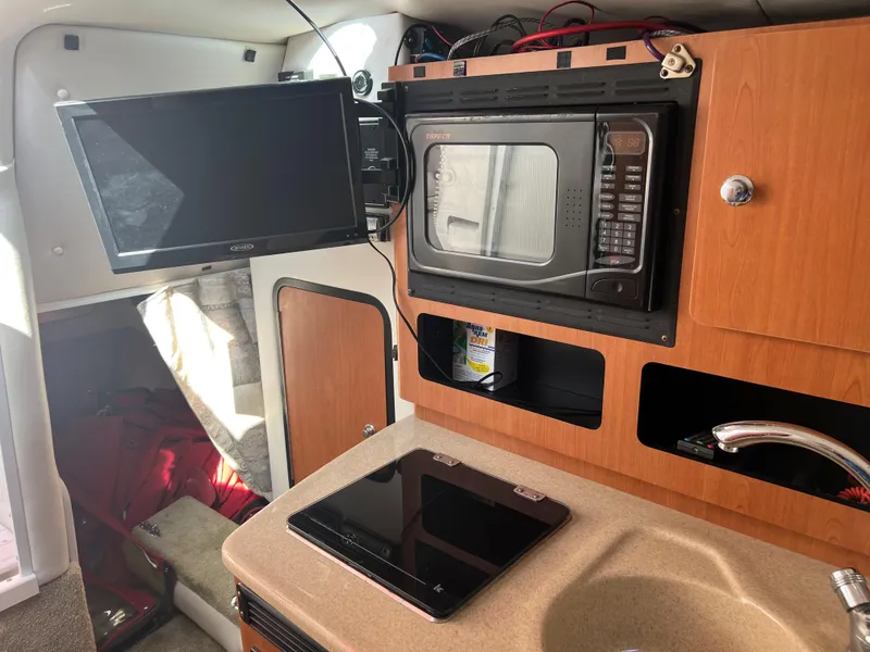 Slide: The Image of 2007 Crownline 250 CR boat interior with TV, microwave, and kitchenette. - 20
