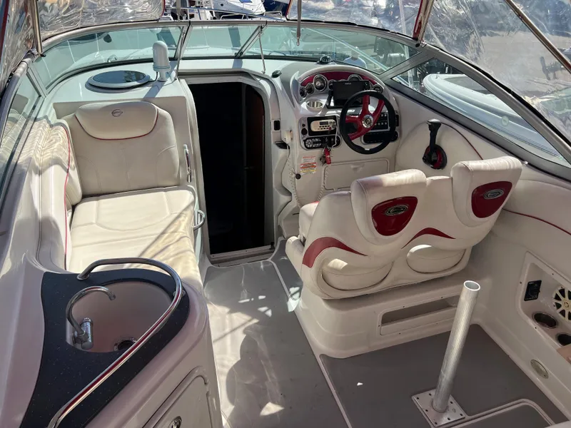 Slide: The Image of 2007 Crownline 250 CR boat interior with white and red seating, steering wheel, and sink. - 8