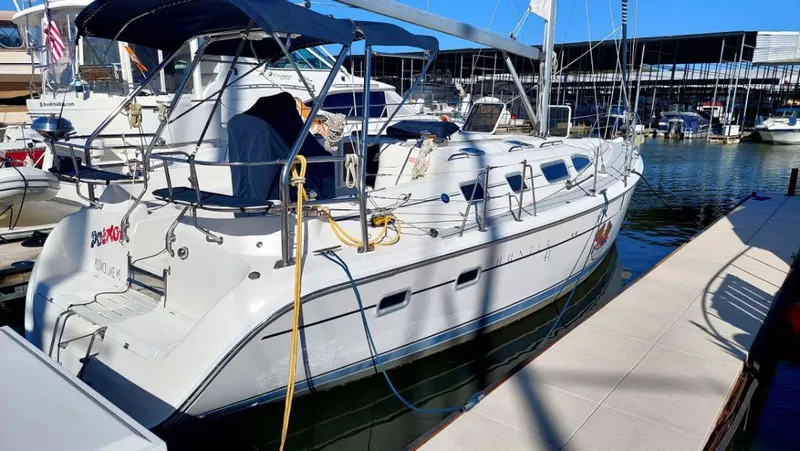 The Image of 2005 Hunter 41 sailboat docked at marina, featuring spacious deck and canopy. - 0
