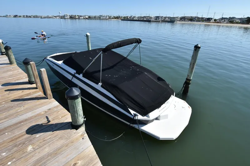 Slide: The Image of 2012 Regal 24 FasDeck boat docked with black cover on calm water. - 3