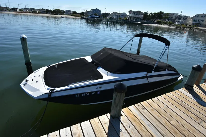 Slide: The Image of 2012 Regal 24 FasDeck boat docked by calm waters, covered and ready for use. - 4